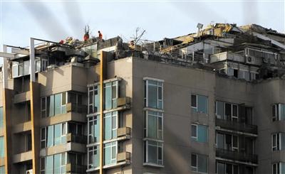 　　昨日，身穿橘黃色馬甲的工作人員在人濟(jì)山莊樓頂拆除違章建筑。新京報(bào)記者 吳江 攝