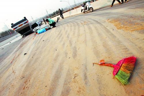 被撞的環(huán)衛(wèi)工躺在地上，身上蓋著藍(lán)色布?jí)K，現(xiàn)場(chǎng)除散落的汽車碎片外，還留有被撞斷的掃帚。