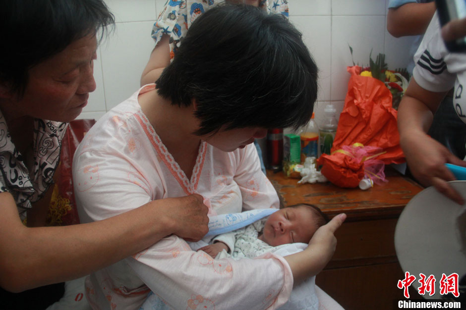 圖為久別重逢，獲救嬰兒母親悉心撫摸愛子。張一辰 攝