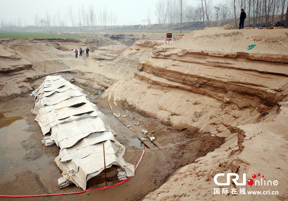 2014年1月6日，河南洛陽古沉船發(fā)掘現(xiàn)場，近日有雨雪天，考古人員給古沉船披上一層“雨衣”。