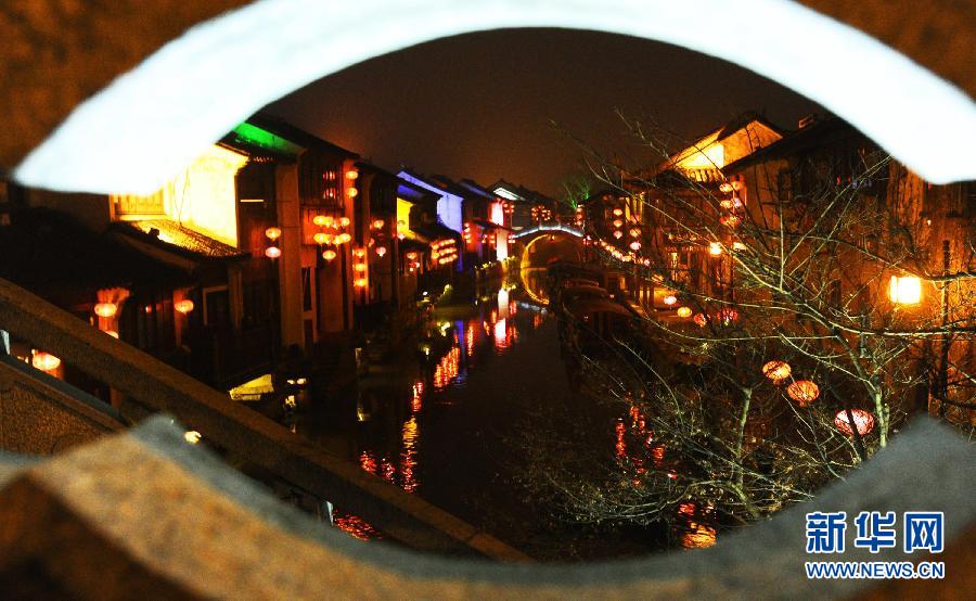 1月30日透過(guò)蘇州市新民橋孔拍攝的山塘古街水巷夜景。