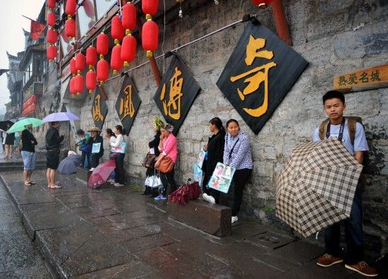 　4月29日上午11時20分，一些游客和古城當?shù)氐木用穸阍谝粋€酒吧的屋檐下避雨。這些當?shù)鼐用褚詾橛慰团恼罩\生，一場降雨讓他們的生意更加清淡。