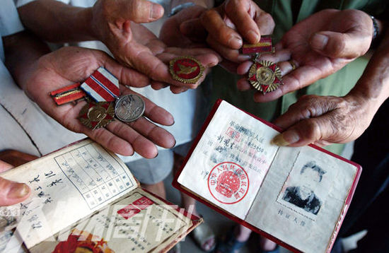 幾位志愿軍老兵展示自己的立功證、傷殘軍人證與勛章