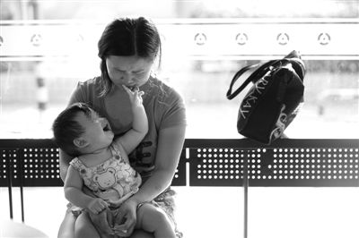 昨日，肯德基京廣中心店門口，姜女士提起跟養(yǎng)父母的關(guān)系時落淚，懷中9個月的女兒笑著跟她玩。新京報記者 薛珺 攝