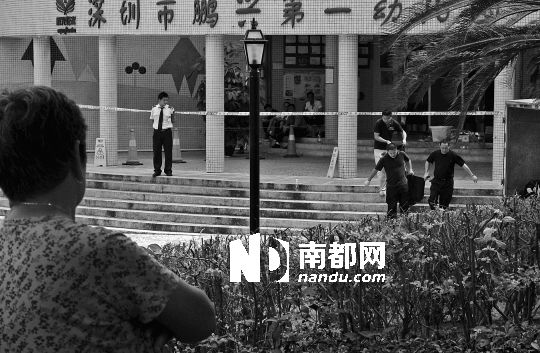 →7月19日，鵬興花園第一幼兒園門前，民警在現(xiàn)場進(jìn)行完勘查取證后，園長和保安的尸體被運走。南都記者 徐文閣 攝