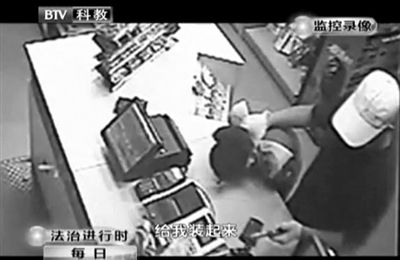 戴帽男子一手掐住加油站營業(yè)員，一手持發(fā)令槍指向另一營業(yè)員，要求“把錢給我裝起來”。