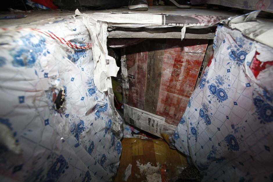 陳小龍?jiān)诔鲎馕萃?，自行又圍起一堵圍墻，安裝了一個(gè)門。圍墻上都是豎起的鐵釘，外面堆著土，鄰居猜是從地底挖出來的。洞口就在床邊，0.5米見方，深約1.5米。洞口表面一塊紙板掩蓋，打開紙板跳入洞底，是一扇小木門，木門外有插銷，可以從外面鎖上。