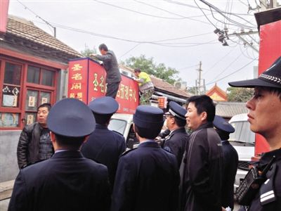 昨日下午,東城區(qū)工商、城管、公安等部門,對雍和宮附近的預(yù)測中心進行清理整頓,站在車頂?shù)膬擅と苏鸪患摇邦A(yù)測中心”的招牌。因雍和宮、白云觀等文化景點外聚集大量算命先生,被媒體稱為“算命一條街”。本版攝影/新京報記者 李寧 攝