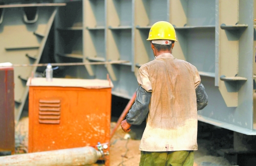 工地上，一建筑工人的衣服被汗水浸透。