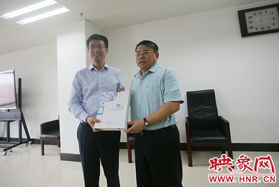 阿里云計(jì)算總裁胡曉明向河南省新聞出版廣電局局長朱夏炎遞交《中原云平臺交付手冊》。