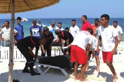6月26日，在突尼斯蘇塞，救生員和醫(yī)務(wù)人員在發(fā)生襲擊事件的海灘運(yùn)送一名死者的遺體。新華社發(fā)