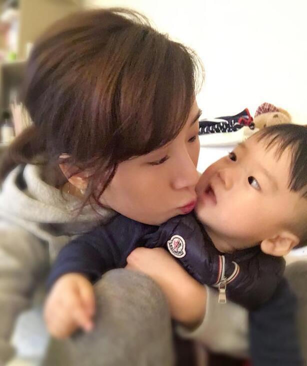 照片中李念狂吻兒子，小寶貝自顧自地玩著。