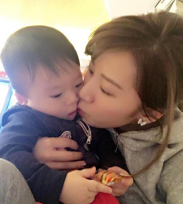 照片中李念狂吻兒子，小寶貝自顧自地玩著。