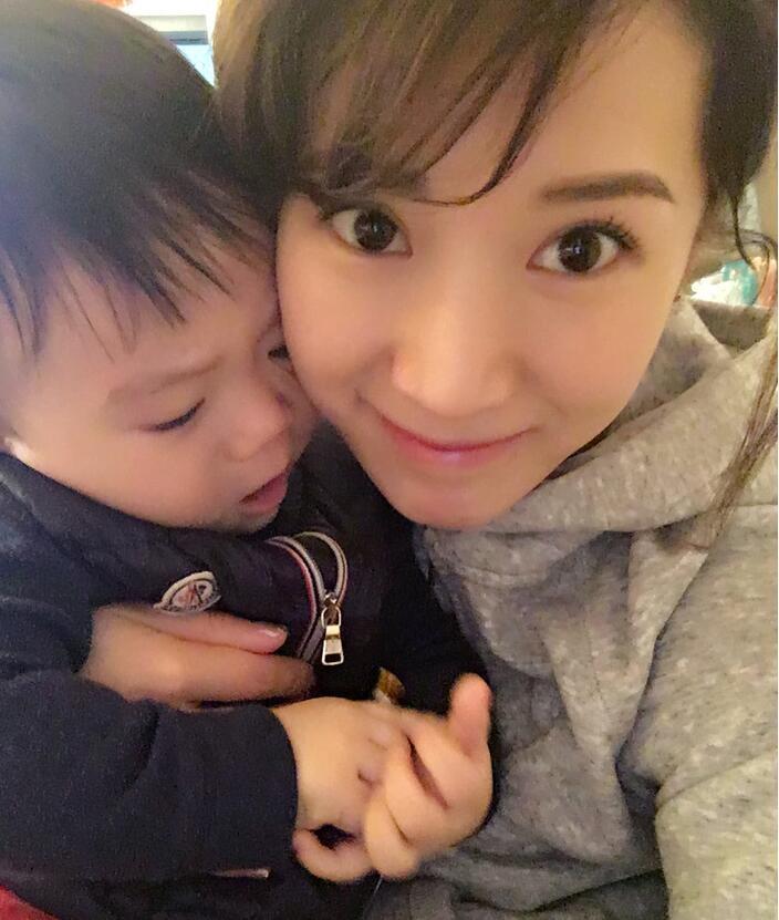 照片中李念狂吻兒子，小寶貝自顧自地玩著。