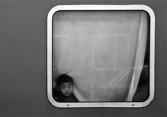 一個孩子把頭伸向窗外，他想再看送別的親人一眼