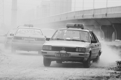施工的道路上，車輛通過塵土飛揚(yáng)。