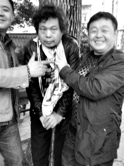 兩名接訪人員與患有癌癥的訪民段新德合影時，面帶笑容擺出勝利的手勢。