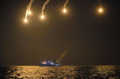 22日，搜救人員在照明彈的光亮下連夜搜救。