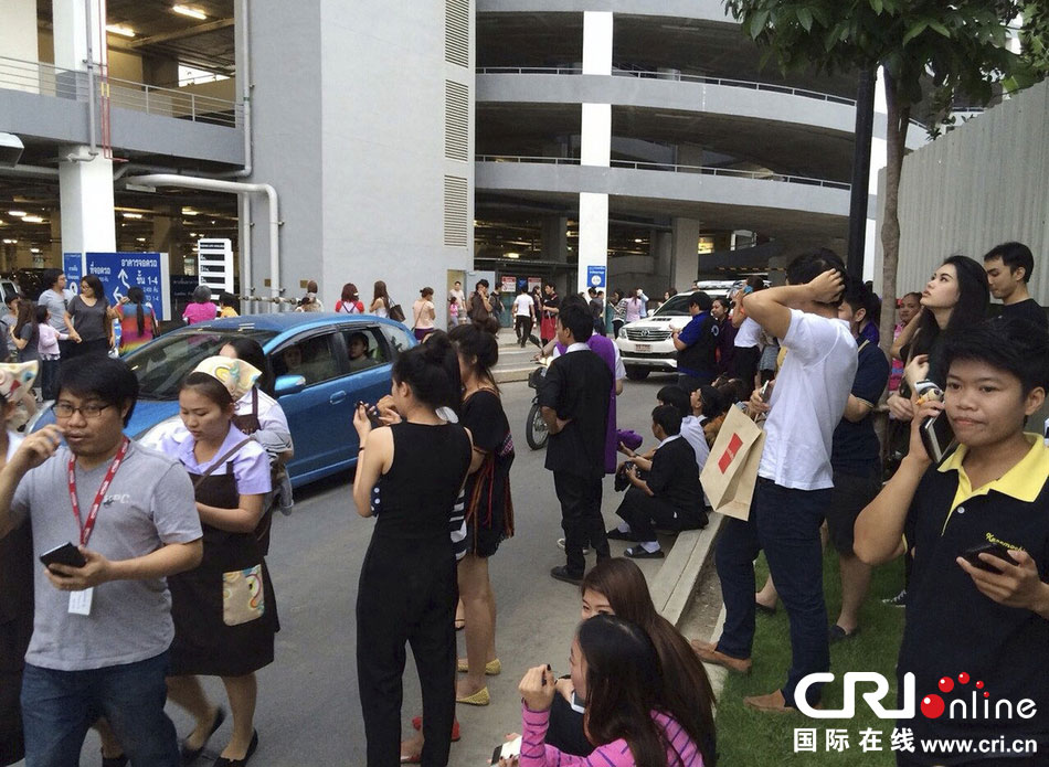 當(dāng)?shù)貢r(shí)間2014年5月5日，泰國清萊，工人們站在一棟大樓外避難。