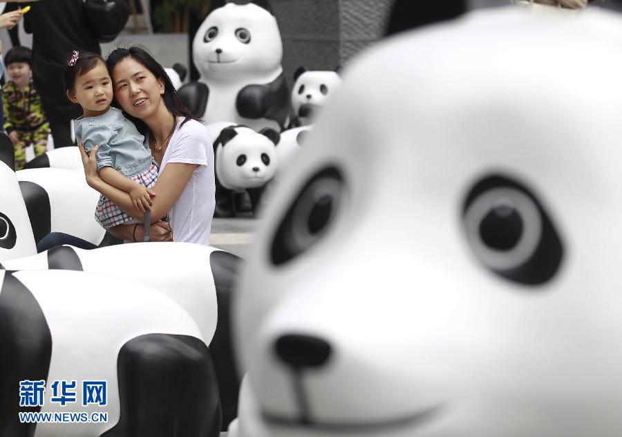6月2日，一位家長帶著孩子在上海街頭和大熊貓模型合影。