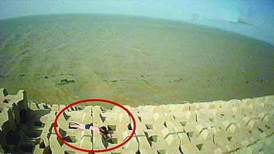 孫正龍游上岸，趴在海邊精疲力盡。