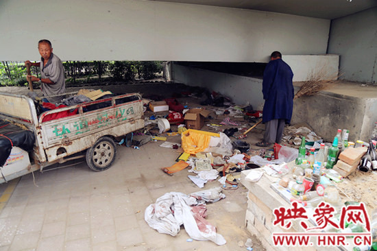 負(fù)責(zé)高架橋下綠化的人員在清理流浪漢留下的垃圾和雜物。