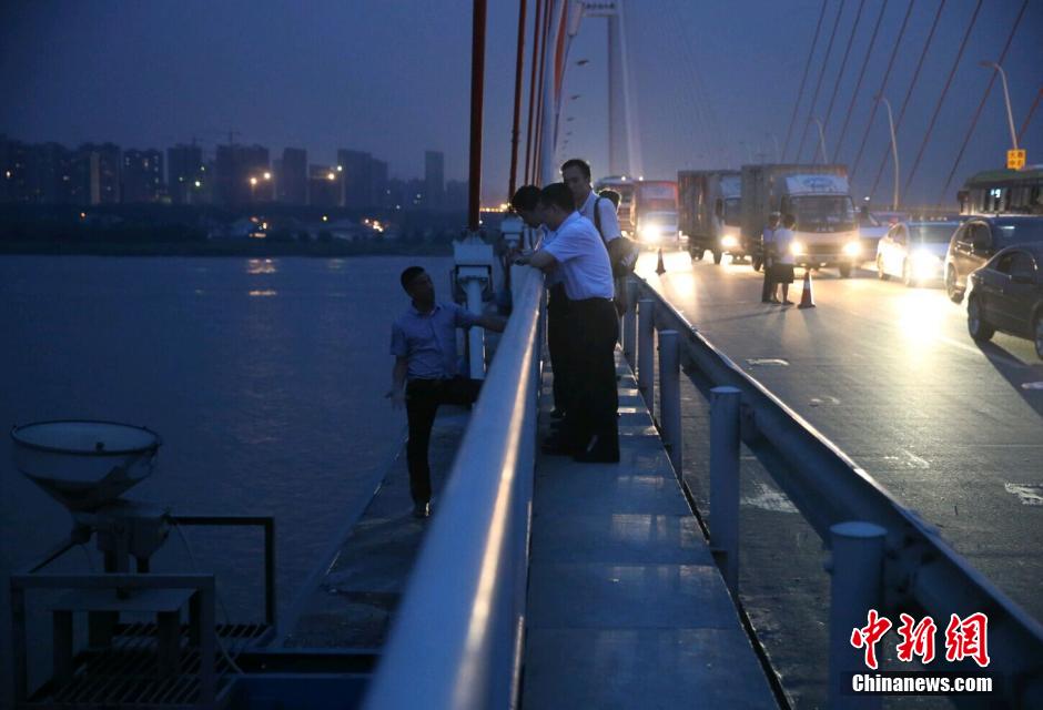 圖為武漢警方談判專家正在與翻爬至大橋外側(cè)護欄的劫持者談判。