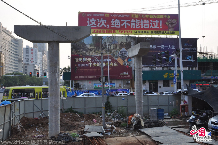 過街天橋一側(cè)的橋樁早已打好,可是對面的郵政銀行網(wǎng)點依舊在照常營業(yè)。