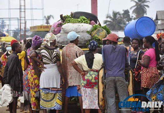 當(dāng)?shù)貢r間2014年8月14日，利比里亞蒙羅維亞，市場里的商人們圍著一輛汽車。