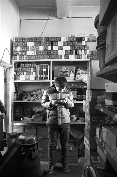 1月21日，周瑋在自家的超市里玩計(jì)算器。